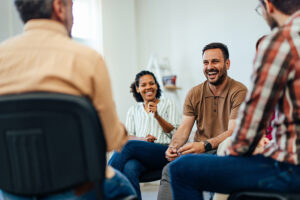 A man smiles in a support group while working on overcoming his fear of attending 12-step meetings.